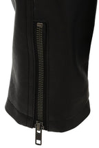 Close-up of a black jacket or pants leg with a vertical metal zipper running down the front, shown against a plain white background.