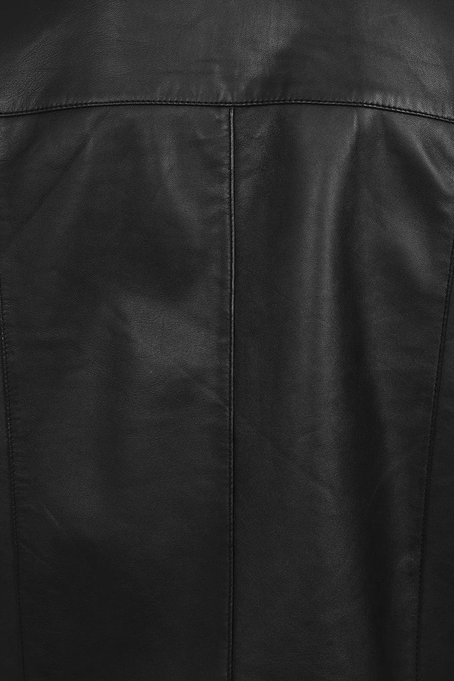 Close-up of a black leather jacket showing the back panel with a central vertical seam and stitched panel seams.
