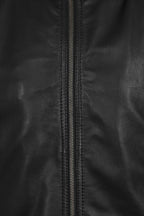 Close-up of a black leather jacket with a central metal zipper and visible stitching.